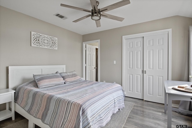 bedroom featuring light wood finished floors, visible vents, a ceiling fan, lofted ceiling, and a closet