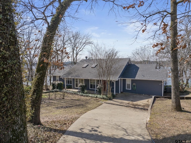 view of front of home featuring concrete driveway, a shingled roof, and central air condition unit