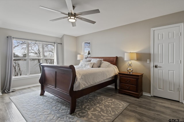 bedroom with ceiling fan, wood finished floors, and baseboards