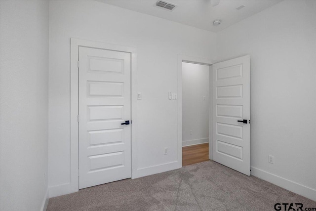 unfurnished bedroom with carpet floors, visible vents, and baseboards