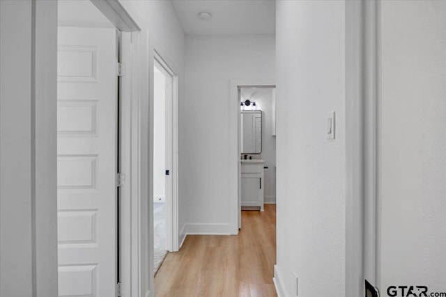 corridor featuring light wood-style floors and baseboards