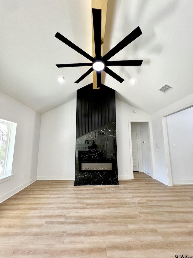 unfurnished living room with lofted ceiling, wood finished floors, a ceiling fan, and a high end fireplace