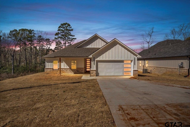 view of front facade featuring concrete driveway, board and batten siding, an attached garage, and a lawn