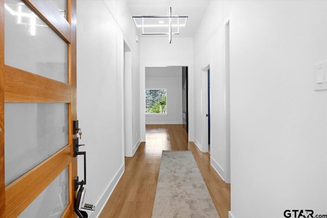 hall with attic access, baseboards, and wood finished floors