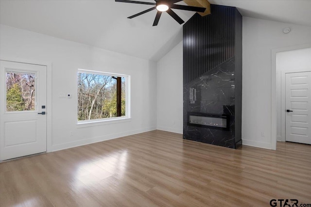 unfurnished living room featuring a high end fireplace, light wood-type flooring, and baseboards