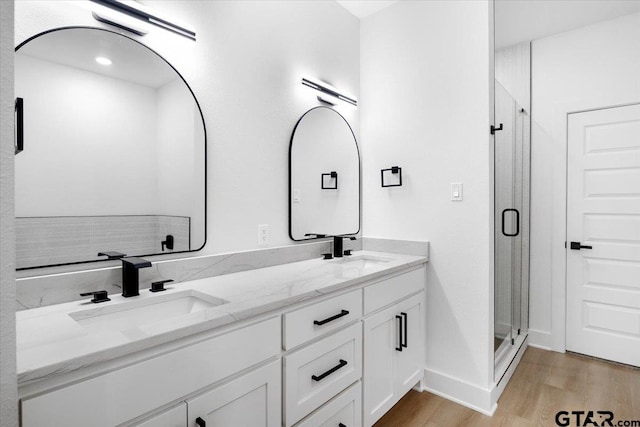 full bathroom featuring wood finished floors, a sink, and a shower stall