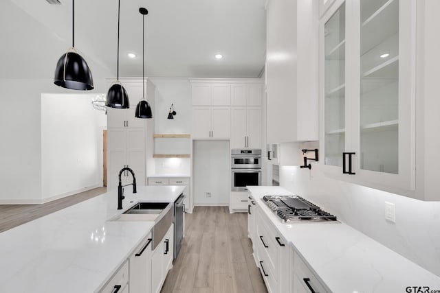 kitchen with appliances with stainless steel finishes, pendant lighting, white cabinets, and light stone countertops