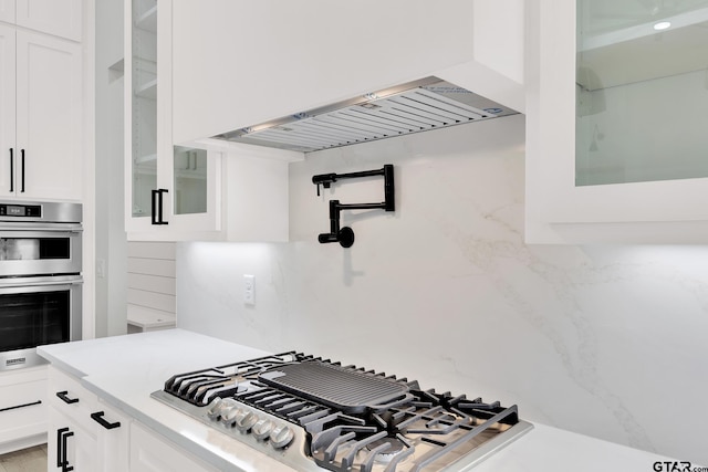 kitchen with white cabinets, decorative backsplash, and appliances with stainless steel finishes