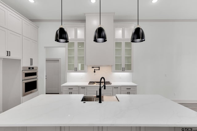 kitchen featuring decorative light fixtures, a kitchen island with sink, sink, and light stone counters