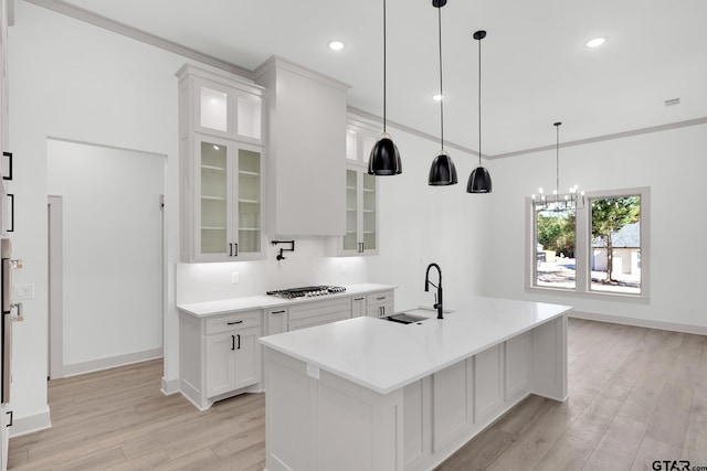 kitchen with white cabinetry, light hardwood / wood-style floors, a center island with sink, stainless steel gas cooktop, and sink