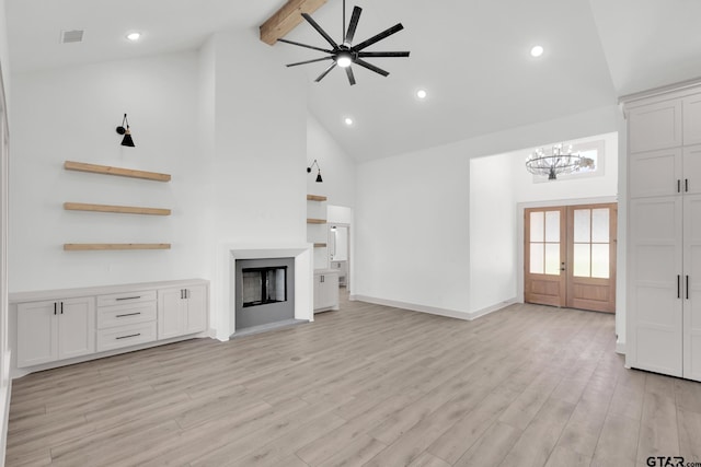 unfurnished living room featuring light wood-type flooring, ceiling fan with notable chandelier, french doors, and high vaulted ceiling