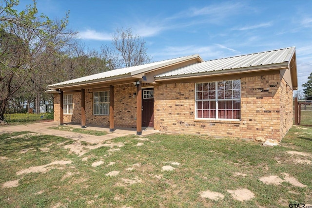 single story home featuring brick siding, a front yard, and metal roof