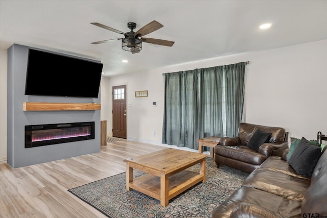 living room with a ceiling fan, recessed lighting, a glass covered fireplace, and wood finished floors