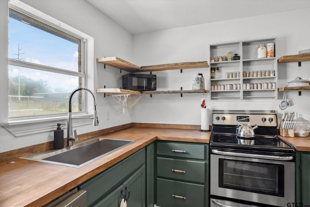 kitchen with green cabinets, a sink, open shelves, and electric stove