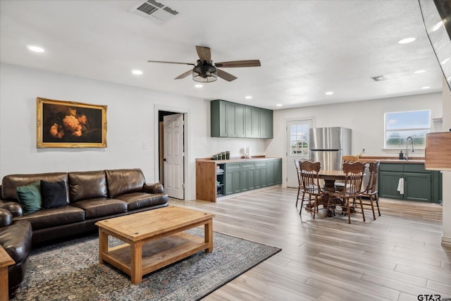 living room with a ceiling fan, recessed lighting, light wood finished floors, and visible vents