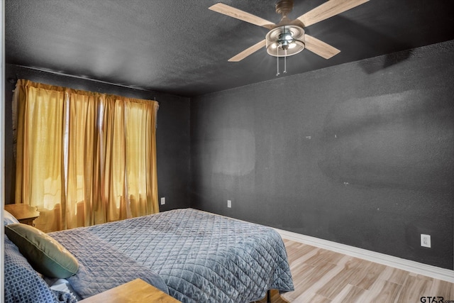 bedroom with baseboards, wood finished floors, and a textured ceiling
