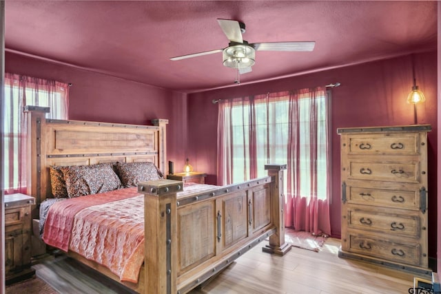 bedroom featuring ceiling fan, wood finished floors, and multiple windows