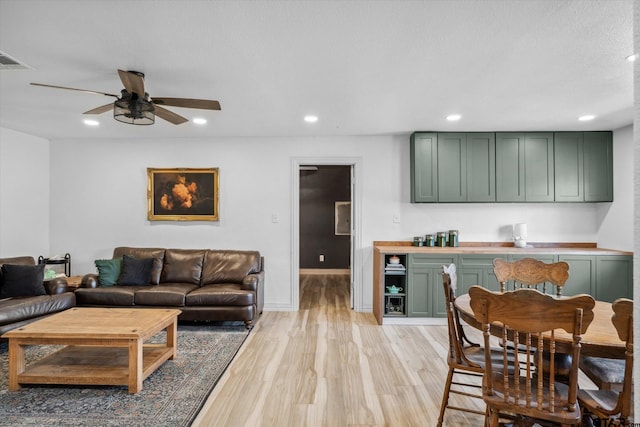 living room featuring visible vents, baseboards, recessed lighting, a ceiling fan, and light wood-style floors