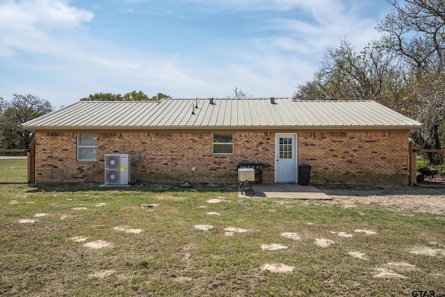 back of property with metal roof, brick siding, a yard, and a patio area