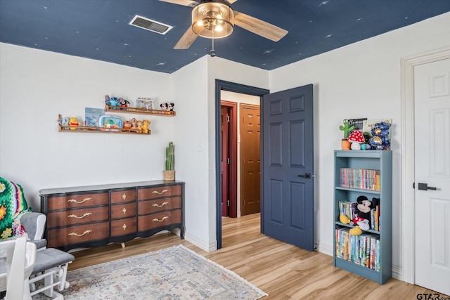bedroom featuring baseboards, visible vents, light wood-style floors, and a ceiling fan