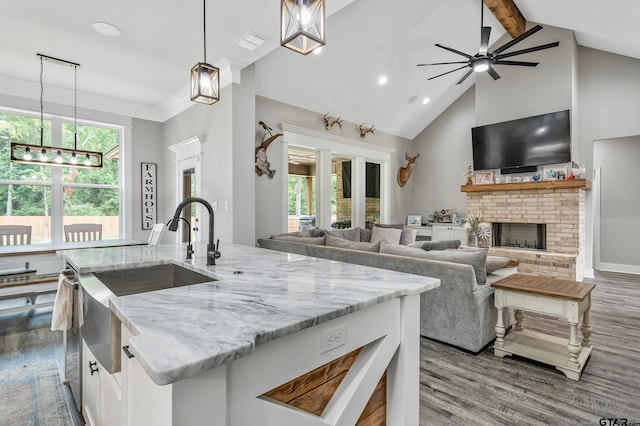 kitchen with white cabinets, decorative light fixtures, light stone counters, and a brick fireplace