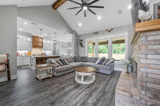 living room with beam ceiling, ceiling fan, dark wood-type flooring, a brick fireplace, and high vaulted ceiling