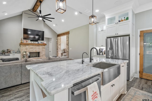 kitchen featuring light stone countertops, white cabinetry, stainless steel dishwasher, and a kitchen island with sink