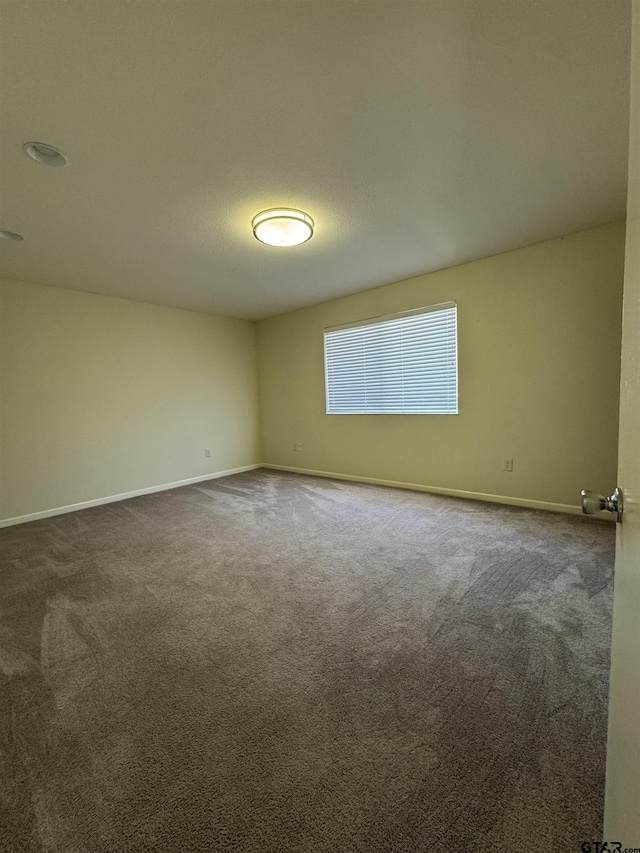 carpeted spare room featuring baseboards