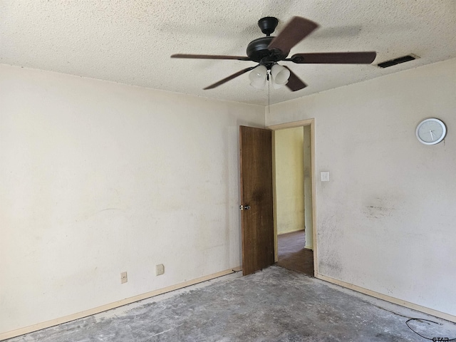 empty room with a textured ceiling, ceiling fan, concrete floors, and visible vents