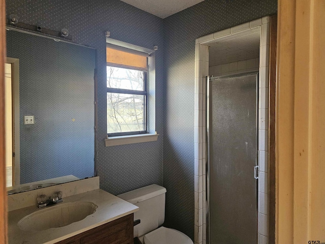 full bathroom with toilet, wallpapered walls, a shower stall, and vanity