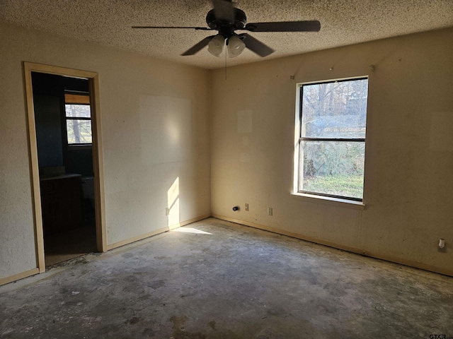 spare room featuring a wealth of natural light, concrete floors, and a textured ceiling