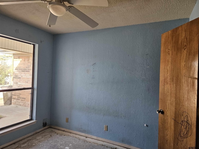 unfurnished room featuring ceiling fan, baseboards, a textured ceiling, and a textured wall