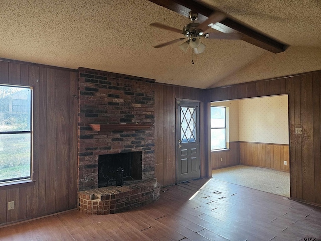 foyer entrance with a ceiling fan, hardwood / wood-style flooring, vaulted ceiling with beams, a textured ceiling, and wood walls