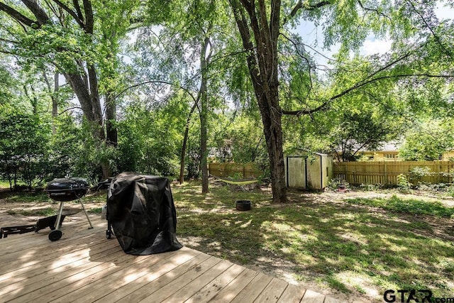 wooden deck featuring a fenced backyard, an outbuilding, a storage shed, and a grill