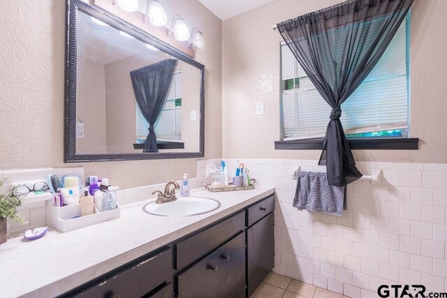 bathroom featuring a wainscoted wall, vanity, tile patterned floors, and tile walls