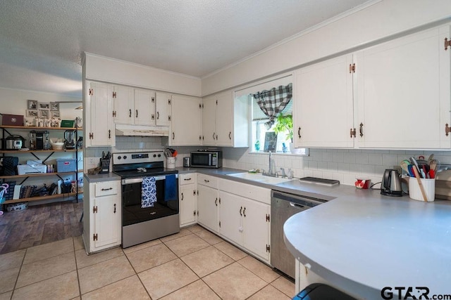 kitchen with decorative backsplash, appliances with stainless steel finishes, a sink, under cabinet range hood, and white cabinetry