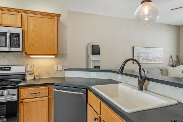 kitchen with dark countertops, open floor plan, a sink, stainless steel appliances, and backsplash