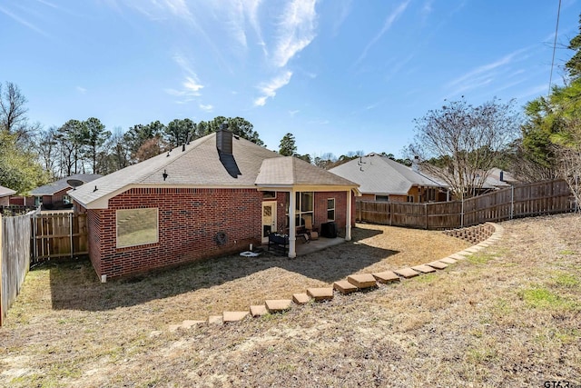 back of house with brick siding, a chimney, a patio area, and a fenced backyard