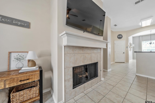 living area featuring light tile patterned floors, a fireplace, visible vents, and baseboards