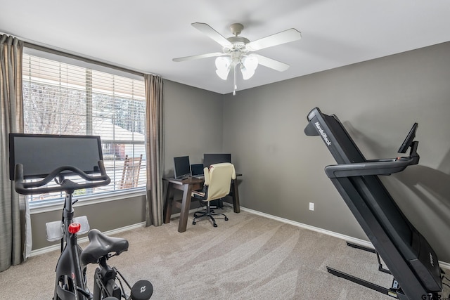 carpeted office space with a ceiling fan and baseboards