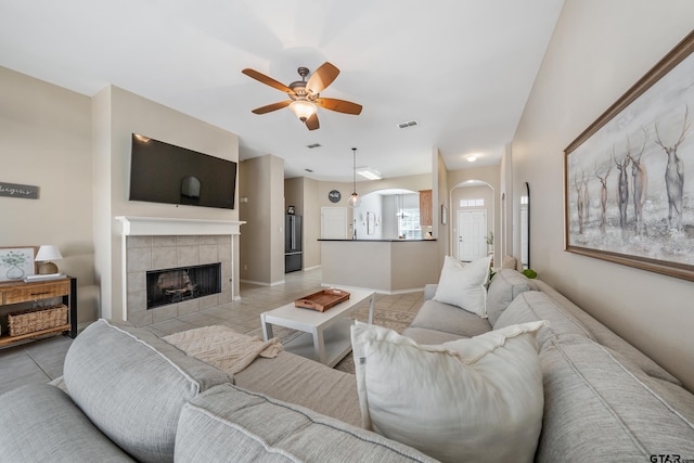 living room featuring a fireplace, light tile patterned floors, visible vents, a ceiling fan, and baseboards