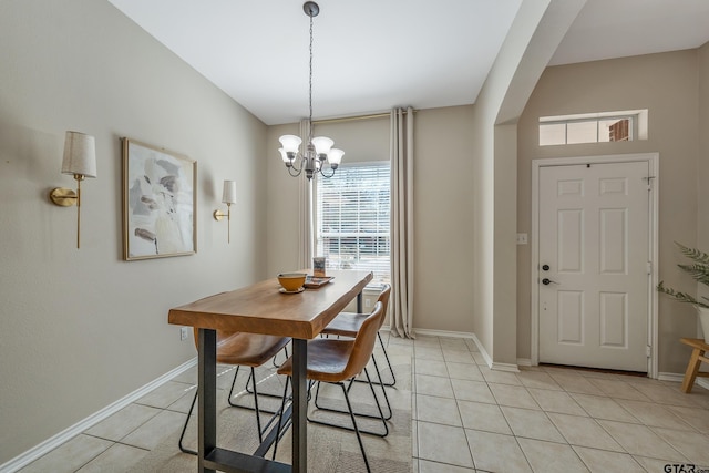 dining room featuring light tile patterned floors, arched walkways, a chandelier, and baseboards