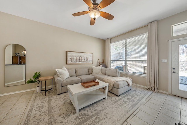 living room with light tile patterned flooring, ceiling fan, and baseboards