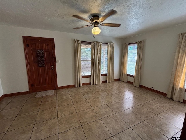 tiled spare room with a textured ceiling and ceiling fan