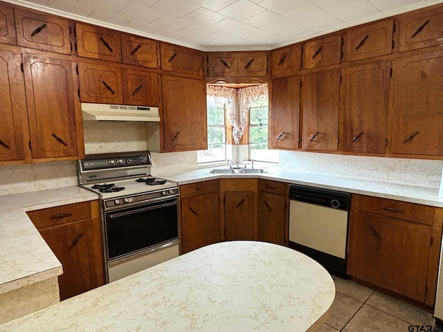 kitchen featuring white dishwasher, stove, sink, and light tile patterned floors