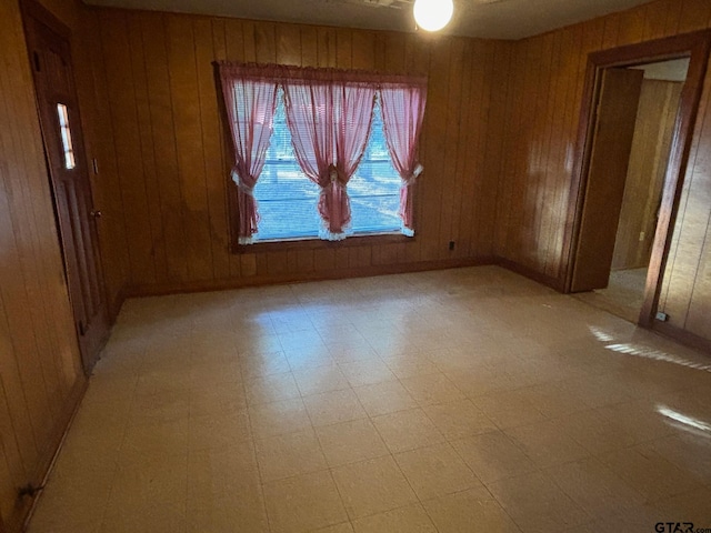 empty room featuring wooden walls and ceiling fan