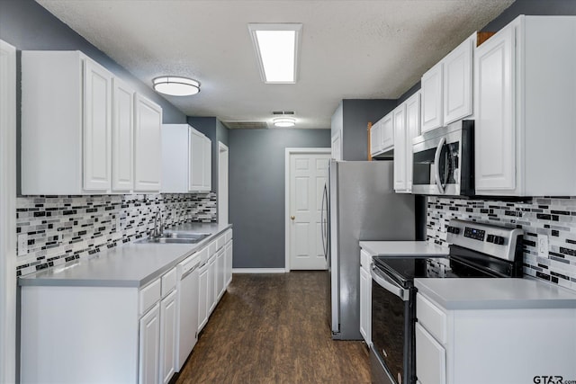 kitchen with appliances with stainless steel finishes, dark hardwood / wood-style flooring, tasteful backsplash, sink, and white cabinets