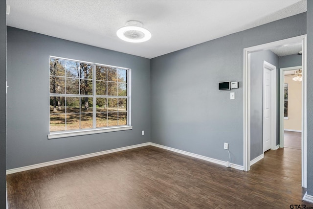 empty room with a textured ceiling and dark hardwood / wood-style floors