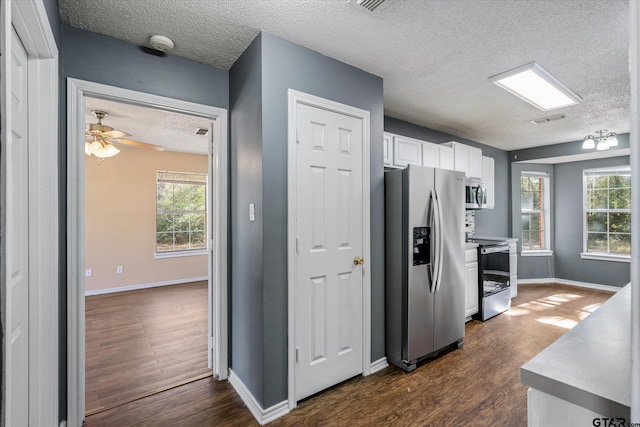 kitchen featuring dark hardwood / wood-style flooring, a textured ceiling, stainless steel appliances, ceiling fan, and white cabinets