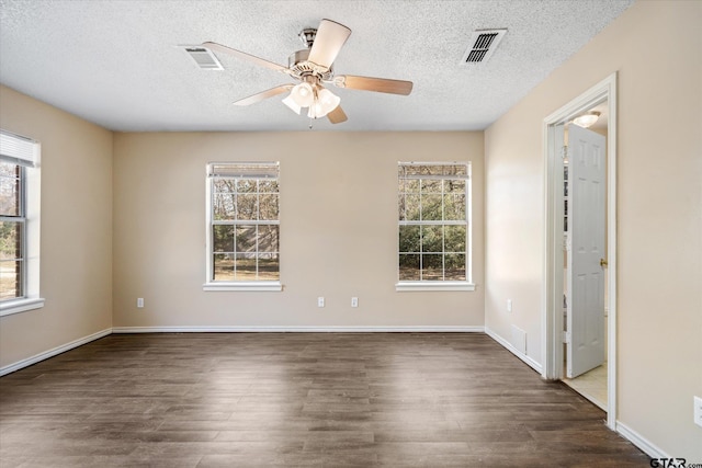 spare room with a textured ceiling, ceiling fan, a healthy amount of sunlight, and dark hardwood / wood-style floors